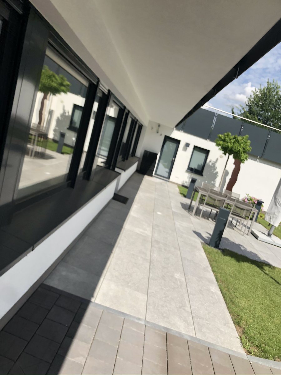 Sonnige Terrasse entlang der Glasfront